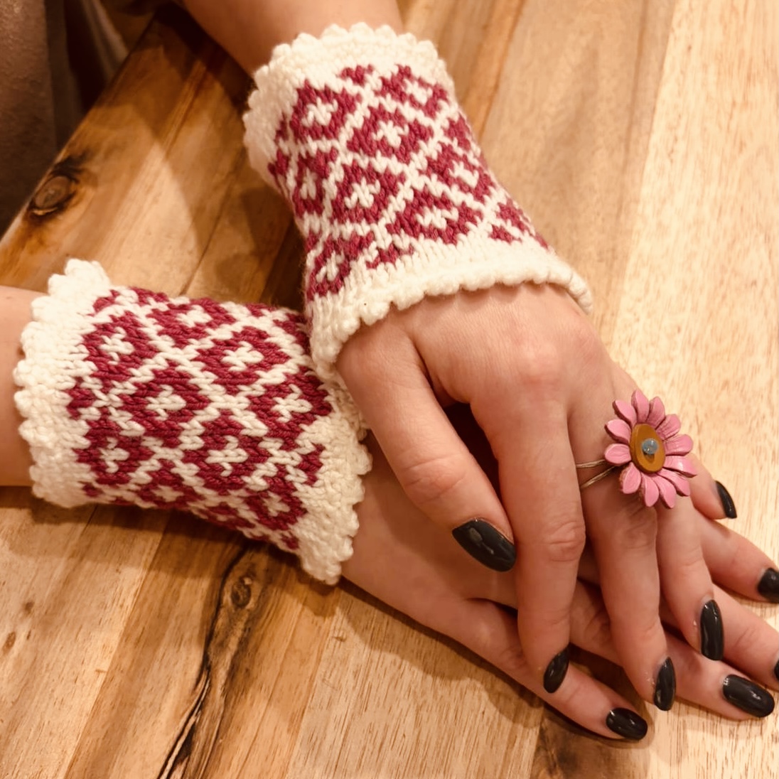 Handgestrickte Pulswärmer mit rot-weißem Norwegermuster an den Händen